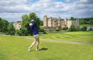 a man playing golf in front of a castle at Leeds Castle Stable Courtyard Bed and Breakfast in Maidstone