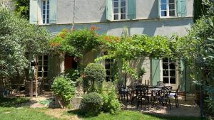 a garden with a table and chairs in front of a house at LA FUGUE chambres d' hôtes de charme , DEMEURE HISTORIQUE,PISCINE,JARDIN proche UZES NIMES ALES in Brignon