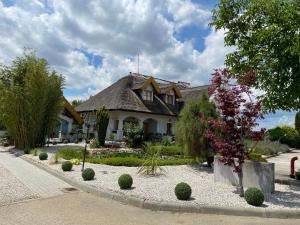 a house with a thatched roof and a gravel driveway at Rigótanya Relax & Wellness Bükfürdő in Bük