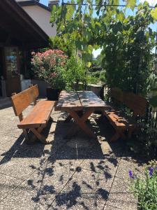 una mesa de picnic de madera y 2 bancos en un patio en Garni Guflhof, en Caldaro