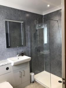 a bathroom with a glass shower and a sink at Springwood in Seahouses