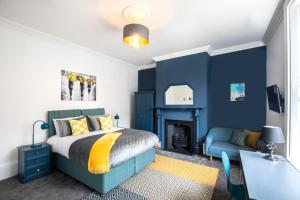 een slaapkamer met blauwe muren en een bed en een bureau bij BrickSage Rooms, King's Lynn South Gate in Kings Lynn