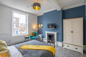 BrickSage Rooms, King's Lynn South Gate في كينغز لين: غرفة نوم زرقاء مع سرير ومدفأة