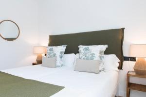 a bedroom with a white bed with a green headboard and pillows at 2Casas in Pontevedra +33 photos