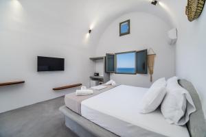 a hotel room with a bed and a television at Amethyst Luxury Suites Oia in Thólos