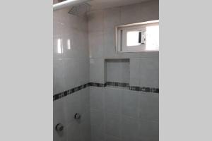 eine weiß geflieste Dusche mit Fenster im Bad in der Unterkunft Posada Tres Marías Un rincón de Magia Zacateca. in Zacatlán