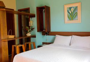 um quarto com uma cama branca e uma parede azul em Pousada Chão da Serra em Serra do Cipó