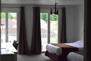 ブルボンヌ・レ・バンにあるHotel des Lauriers Rosesのベッド2台と大きな窓が備わるホテルルームです。