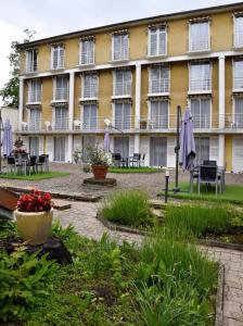 a large yellow building with tables and chairs at Hotel des Lauriers Roses in Bourbonne-les-Bains