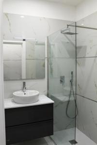 een badkamer met een wastafel en een glazen douche bij Loft Eleonora D’Arborea in Quartu SantʼElena