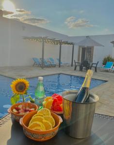 a table with fruit and a bottle of champagne and a pool at Hotel Bella Isa in La Dorada