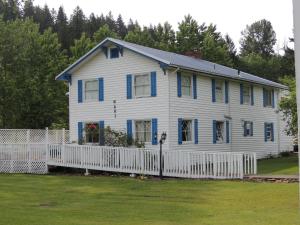a white house with blue windows and a white fence at Foster Lake Inn in Sweet Home