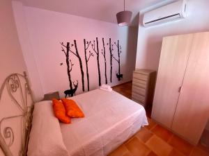 1 dormitorio con 1 cama con almohadas de naranja y árboles en la pared en Alojamiento Los Tejos - Arroyo Frío, en Arroyo Frío
