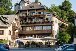 ein Hotelgebäude mit Sonnenschirmen davor in der Unterkunft POST AM SEE in Traunkirchen