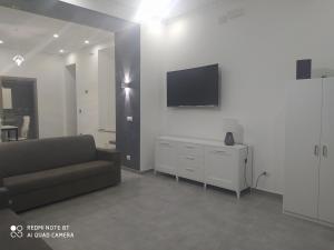 sala de estar con sofá y TV en la pared en MONOLOCALE-ALI', en Alì