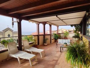 un patio con 2 sillas blancas y una mesa en "Appartamento del Mare Gliaca" con vista Isole Eolie,ampia terrazza,wifi e parcheggio gratuito, en Piraino