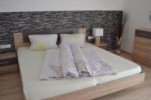 ein Bett mit weißer Bettwäsche und Kissen darauf in der Unterkunft Appartement Thermenzeit in Längenfeld