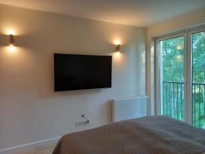 a bedroom with a flat screen tv on the wall at Leśny Kąt in Ustka