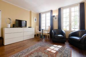 uma sala de estar com uma televisão e uma mesa e cadeiras em Paris Saint Michel Sorbonne em Paris