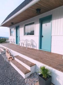 a house with a wooden deck with chairs on it at En route vers l’infini in Perce