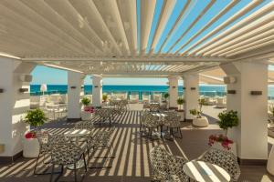 a patio with tables and chairs and the ocean in the background at RH Bayren Hotel & Spa 4* Sup in Gandía