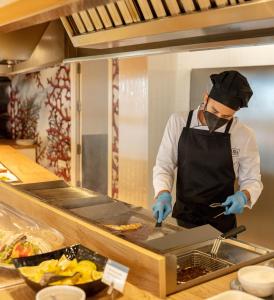 
a man in a chef's outfit preparing food in a kitchen at RH Bayren Hotel & Spa 4* Sup in Gandía
