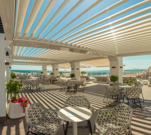 a patio with tables and chairs and the ocean at RH Bayren Hotel & Spa 4* Sup in Gandía