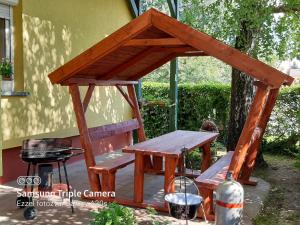 a wooden pergola with a table and a bench at Tilesch Apartment in Balatonberény