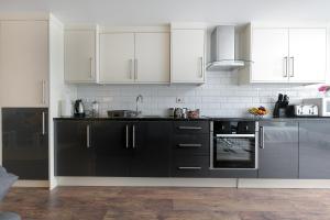a kitchen with black appliances and white cabinets at KVM - City Apartments in Peterborough