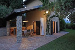 dom z patio ze stołem i krzesłami w obiekcie Villa Bouganville w mieście Toscolano Maderno