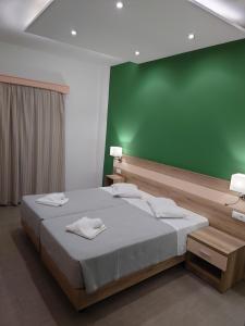 1 dormitorio con 1 cama grande y pared verde en Ifigenia Hotel, en Skiathos