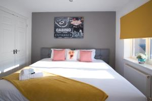 a bedroom with a large white bed with pink pillows at Bank Side House by KVM Stays in Peterborough