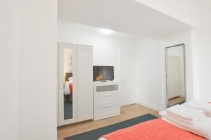 ein weißes Schlafzimmer mit Fernseher und Spiegel in der Unterkunft No 8 Westbay Apartment in Oban