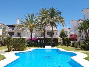 a swimming pool in front of a house with palm trees at Los Naranjos close to Puerto Banus in Marbella