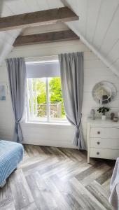 sypialnia z oknem i drewnianą podłogą w obiekcie Żółte Drzwi Sucha Rzeczka w mieście Sucha Rzeczka