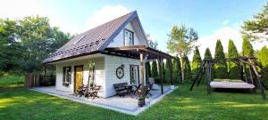 mały biały dom z huśtawką i gankiem w obiekcie Żółte Drzwi Sucha Rzeczka w mieście Sucha Rzeczka