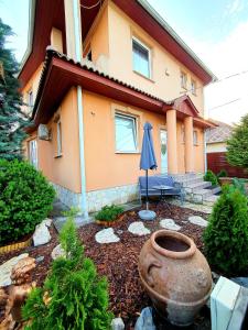 a house with a vase and an umbrella in a yard at Airport Luxury Apartman 42 in Vecsés