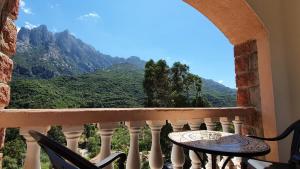 a balcony with a table and chairs and mountains at Hôtel Bella Vista in Porto Ota