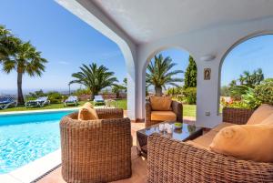 an outdoor patio with wicker furniture and a swimming pool at Casa Media Luna, Mijas Malaga in Mijas