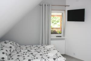 a white bedroom with a bed and a window at Kama Pokoje Gościnne in Białowieża