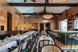 a restaurant with white tables and chairs and a bar at The Colony Palms Hotel and Bungalows - Adults Only in Palm Springs