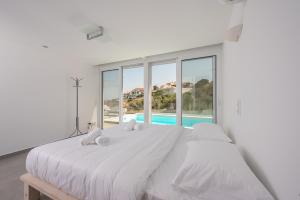 a white bedroom with a large bed and a pool at Villa Luna Private Heated Hydro Pool BBQ Beach 4min in Agia Marina Mikrolimanou