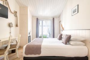 a bedroom with a bed and a desk and a window at Hôtel Restaurant & Spa Plaisir in Le Bois-Plage-en-Ré