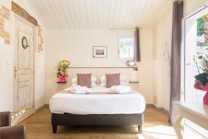 a bedroom with a bed with white sheets and pillows at Hôtel Restaurant & Spa Plaisir in Le Bois-Plage-en-Ré
