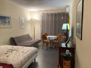 Cette chambre comprend un lit, une table et un canapé. dans l'établissement Meublés de Tourisme Beaulieu, à Beaulieu-sur-Mer