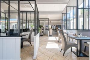 a restaurant with tables and chairs and windows at Hôtel Restaurant & Spa Plaisir in Le Bois-Plage-en-Ré