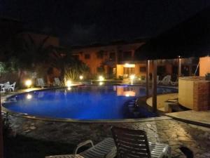 a large swimming pool at night with chairs around it at CostaSol Pipa Chalés in Pipa