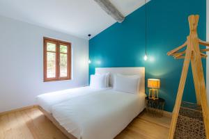 a bedroom with a white bed and a blue wall at Les Pimprenelles in Carcassonne