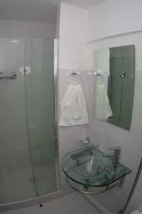 y baño con lavabo de cristal y ducha. en Hotel Esmeralda, en Iquique
