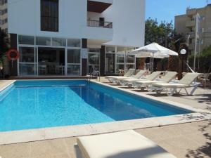 a swimming pool with lounge chairs and a building at Apartamentos Es Cantó in Playa d'en Bossa